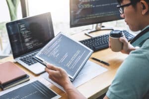 Man working on code at desk with multiple monitors