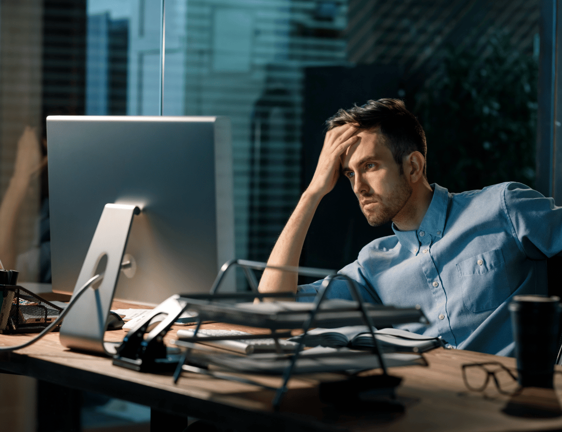 Overwhelmed IT worker at a computer late in the evening